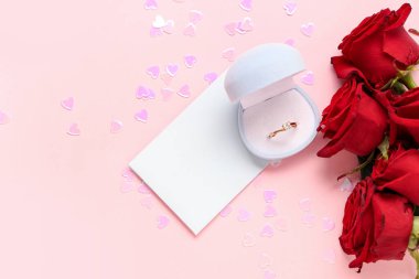 Nişan yüzüğü ve pembe arka planda gül çiçekleri olan güzel bir kompozisyon. Sevgililer Günü kutlaması