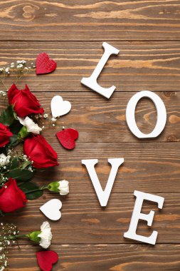 Güzel çiçekler, kalpler ve aşk sözcüğü ahşap arka planda