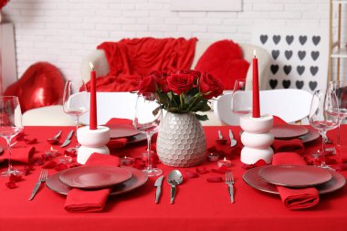 Sevgililer Günü için hazırlanmış şölen masası kırmızı güller ve evde yanan mumlarla süslenmiş.