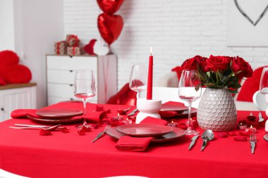 Sevgililer Günü için hazırlanmış şölen masası kırmızı güller ve evde yanan mumlarla süslenmiş.