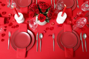 Sevgililer Günü kutlaması için yemek masası, mumlar ve kırmızı güller.