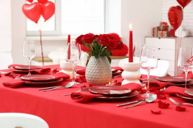 Sevgililer Günü için hazırlanmış şölen masası kırmızı güller ve evde yanan mumlarla süslenmiş.