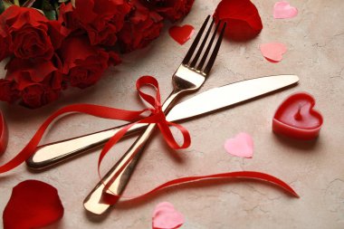 Sevgililer Günü için güzel bir çatal bıçak seti. Kırmızı güller, mum ve bej renginde kalpler.