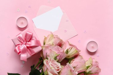 İçinde boş tebrik kartı, hediye kutusu ve pembe arka planda bir buket gül olan bir zarf. Sevgililer Günü kutlaması