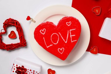 Kalp şeklinde bento pastası, hediye kutuları ve renkli arka planda mumlar. Sevgililer Günü kutlaması