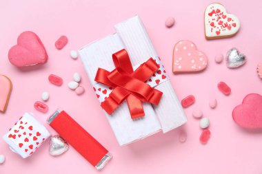 Kalp şeklinde kurabiyeler, farklı tatlılar ve pembe arka planda hediye kutuları. Sevgililer Günü kutlaması