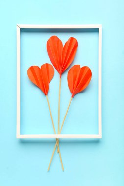 Mavi arkaplanda Sevgililer Günü için çerçeve ve kağıt kalplerle kompozisyon