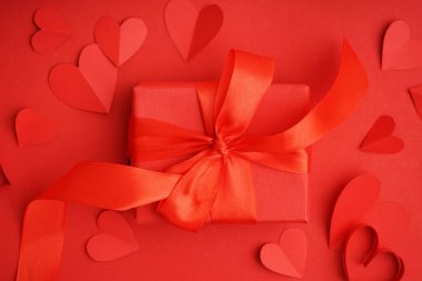 Kağıt kalpli ve kırmızı arka planda hediye kutusu olan güzel bir kompozisyon. Sevgililer Günü kutlaması