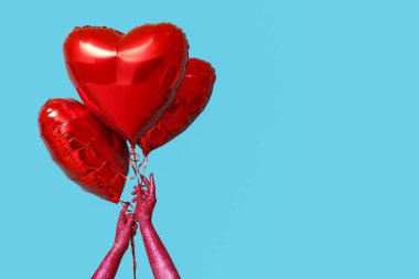 Renkli arka planda kalp şeklinde balonları olan boyalı kadın elleri. Sevgililer Günü kutlaması