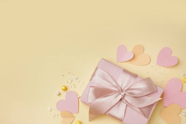 Sarı arka planda karton kalpler ve dekor olan hediye kutusu. Sevgililer Günü kutlaması