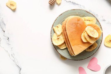 Kalp şeklinde lezzetli gözlemeler ve hafif arka planda kurutulmuş muz tabağı. Sevgililer Günü kutlaması