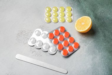 Ağrıyan boğaz için hap, limon ve dil bastırıcı yeşil Grunge arka planda.