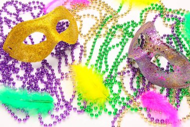 Mardi Gras için renkli boncuklu ve tüylü karnaval maskeleri beyaz arka planda kutlanıyor.