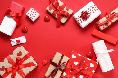Kırmızı arka planda güzel hediye kutuları ve şekerlerden yapılmış çerçeve. Sevgililer Günü kutlaması