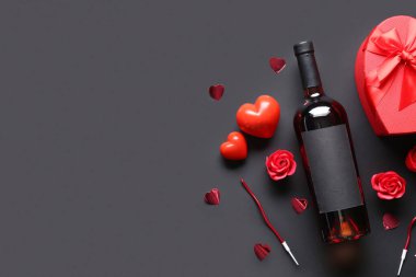Bir şişe şarap, hediye kutusu ve siyah arka planda dekor. Sevgililer Günü kutlaması