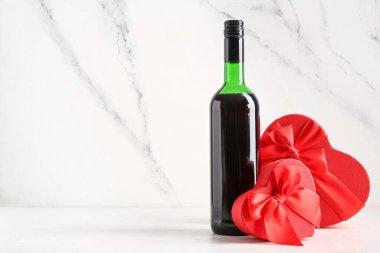 Bir şişe şarap, beyaz masanın üstünde hediyeler, arka plandaki grunge karşı. Sevgililer Günü kutlaması