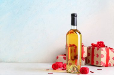 Mavi arka planda beyaz masada hediyeli ve dekorlu bir şişe beyaz şarap. Sevgililer Günü kutlaması