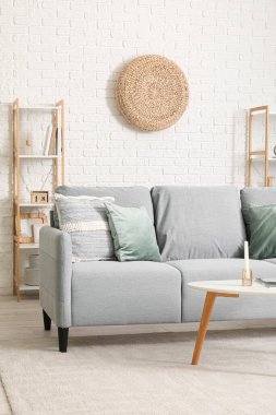 Gri kanepesi ve rattan pouf 'u olan modern oturma odası.