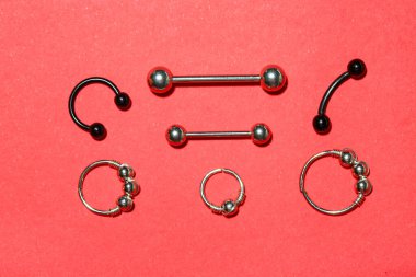 Kırmızı arka planda piercing için şık halkalar ve halkalar