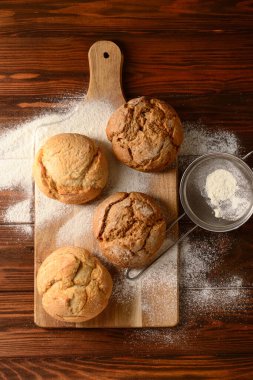 Taze lezzetli çörekler ve ahşap zemin üzerinde un olan bir tahta.