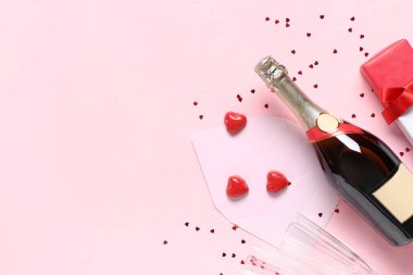 Bir şişe şampanya, gözlüklü, hediye kutusu ve pembe arka planda dekor. Sevgililer Günü kutlaması