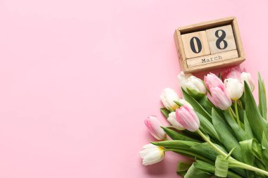 8 Mart tarihli küp takvimi ve pembe arka planda güzel laleler. Uluslararası Kadınlar Günü