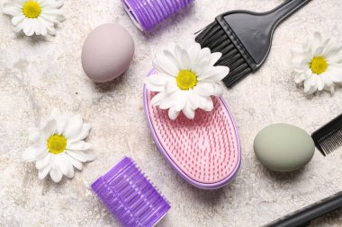 Papatyalı kuaför aksesuarları ve gri grunge arka planda Paskalya yumurtaları.