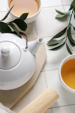 Çaydanlık ve çay fincanlarıyla beyaz fayanslı kompozisyon, yakın plan.