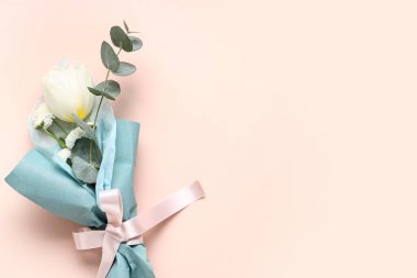 Pembe arka planda ambalaj kağıdına sarılmış küçük bir buket güzel bahar çiçeği. Uluslararası Kadınlar Günü