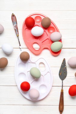 Paletli kompozisyon ve beyaz ahşap arka planda Paskalya yumurtaları. Paskalya konsepti.