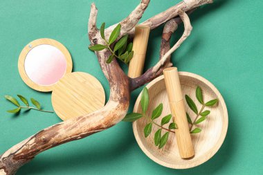 Yeşil arka planda ağaç kabuğu ve dekoratif kozmetik ürünleri olan güzel bir kompozisyon