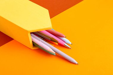 Renkli arka planda farklı kalemlerle ev şeklindeki tutucu