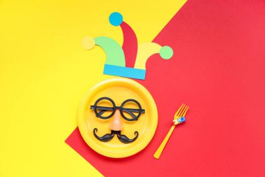Komik gözlükleri ve kağıt palyaço şapkasıyla masa ayarları. Renkli arka planda 1 Nisan şakası için.