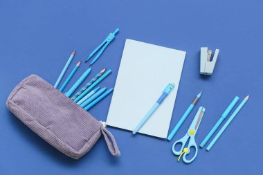 Mavi arka planda kırtasiyeli defter ve kalem çantası. Üst görünüm