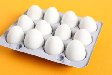 Turuncu arka planda taze haşlanmış bıldırcın yumurtalı tutucu.