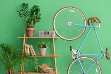 Yeşil duvarın yanında bitkileri ve bisikleti olan raf ünitesi