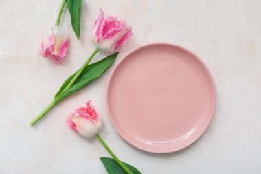 Pembe tabağı ve açık arkaplanda çiçekleri olan güzel bir masa.