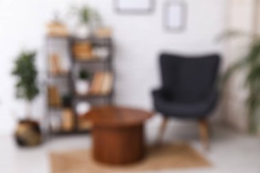 Beyaz tuğla duvarın yanında koltuğu ve kitaplığı olan modern oturma odasının içi bulanık görünüyor.