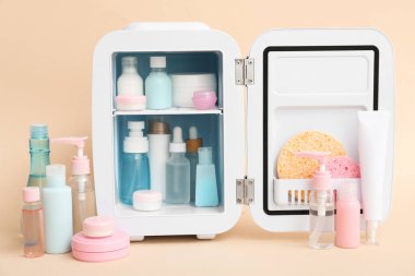 Bej arka planda kozmetik ürünleri olan küçük bir kozmetik buzdolabı