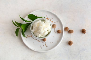 Bir kase tereyağı, fındık ve arkaplanda bitki dalı