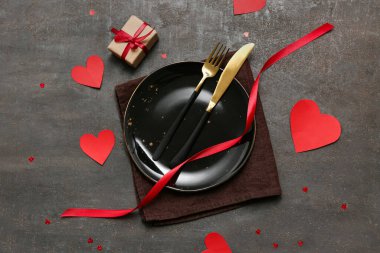 Koyu arkaplanda kağıt kalpler ve hediye kutusuyla Sevgililer Günü için masa ayarı