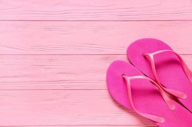 Plaj terlikleri pembe ahşap arka planda