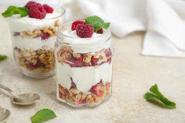 Hafif arka planda yoğurt ve bir kavanoz lezzetli granola, yakın plan.