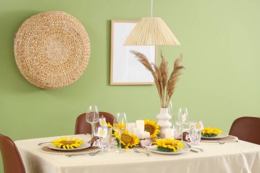 Yeşil duvarın yanında ayçiçekleri olan masa ayarı