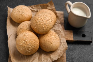Tahta tahta tahta tahtada susam tohumları ve koyu arkaplanda bir sürahi süt.