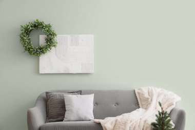 Oturma odasında kanepe, Noel çelengi ve resim var.