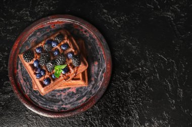 Siyah arka planda taze böğürtlen ve yaban mersinli Belçika Waffle tabağı