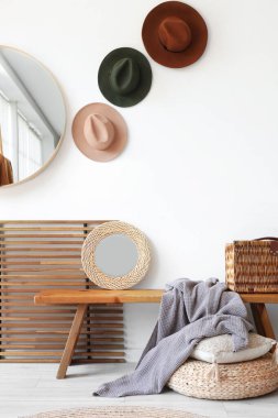 Odanın içinde ahşap bank, şapka ve aynalar var.