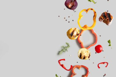 Gri arka planda uçuşan farklı lezzetli ızgara sebzeler.