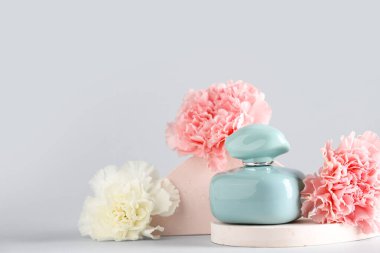 Bir şişe parfüm, alçı tezgahları ve beyaz arka planda karanfiller.